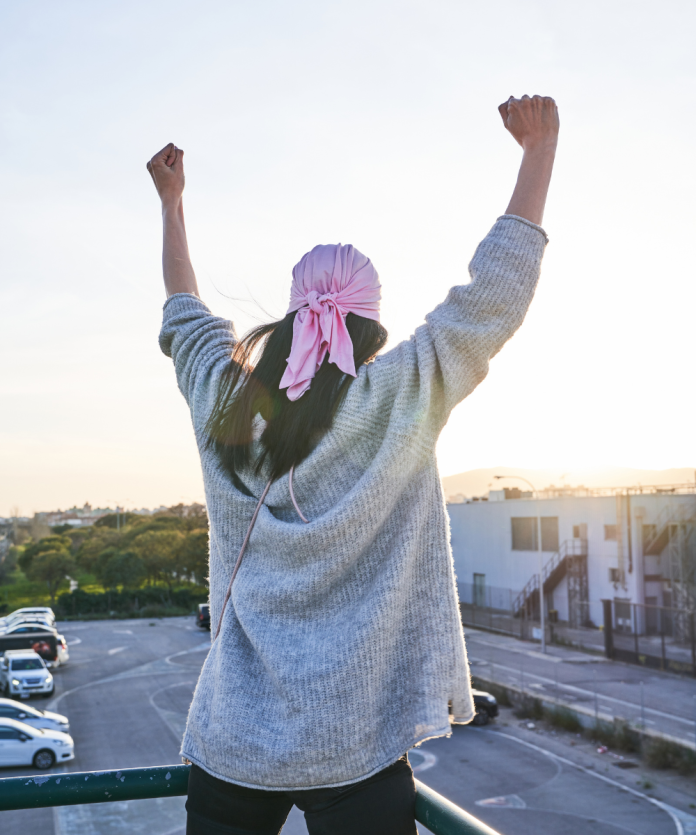 A woman stands tall with her arms raised, exuding confidence and peace of mind, reflecting the reassurance that early breast cancer detection provides.